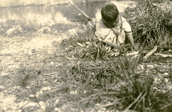 Seminole Indian boy stringing fish at camp on the Tamiami Trail.