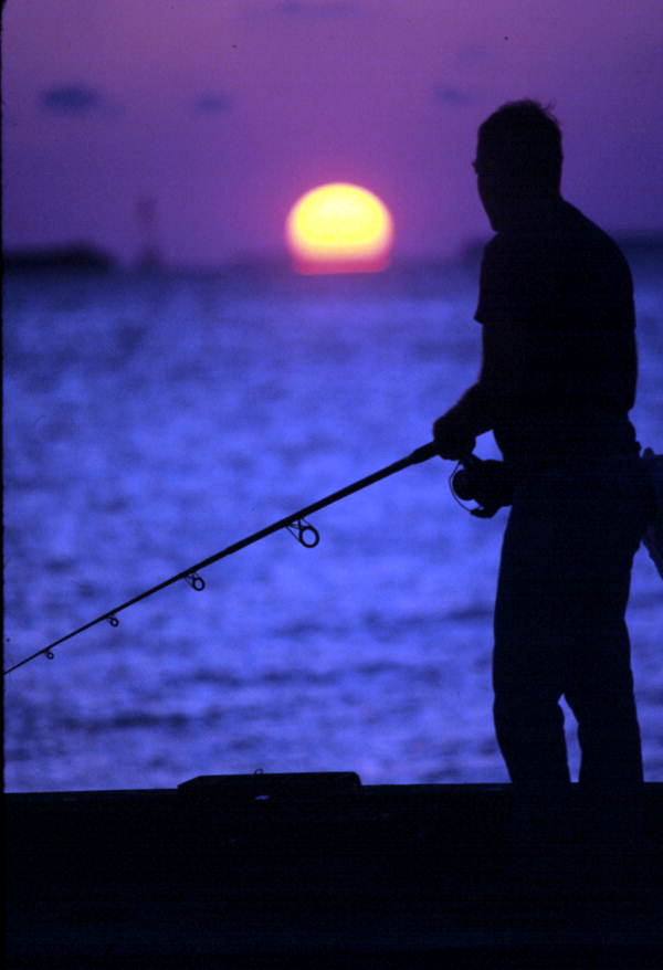 Man fishing at the Navy Outer Mole during sunset - Key West, Florida