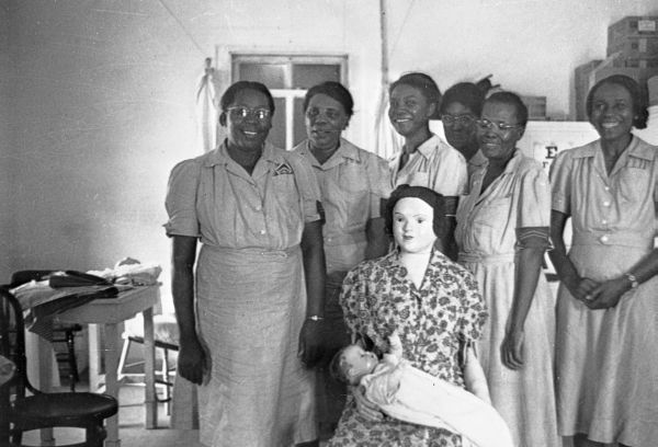 Midwives in training posing for photograph with delivery mannequin