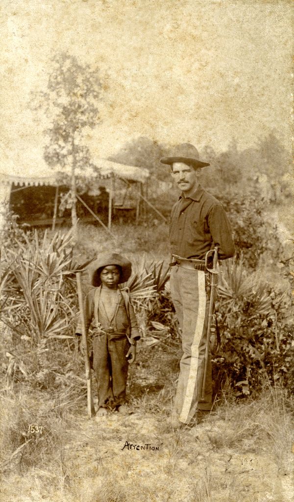 Soldier and boy posing with wooden gun.