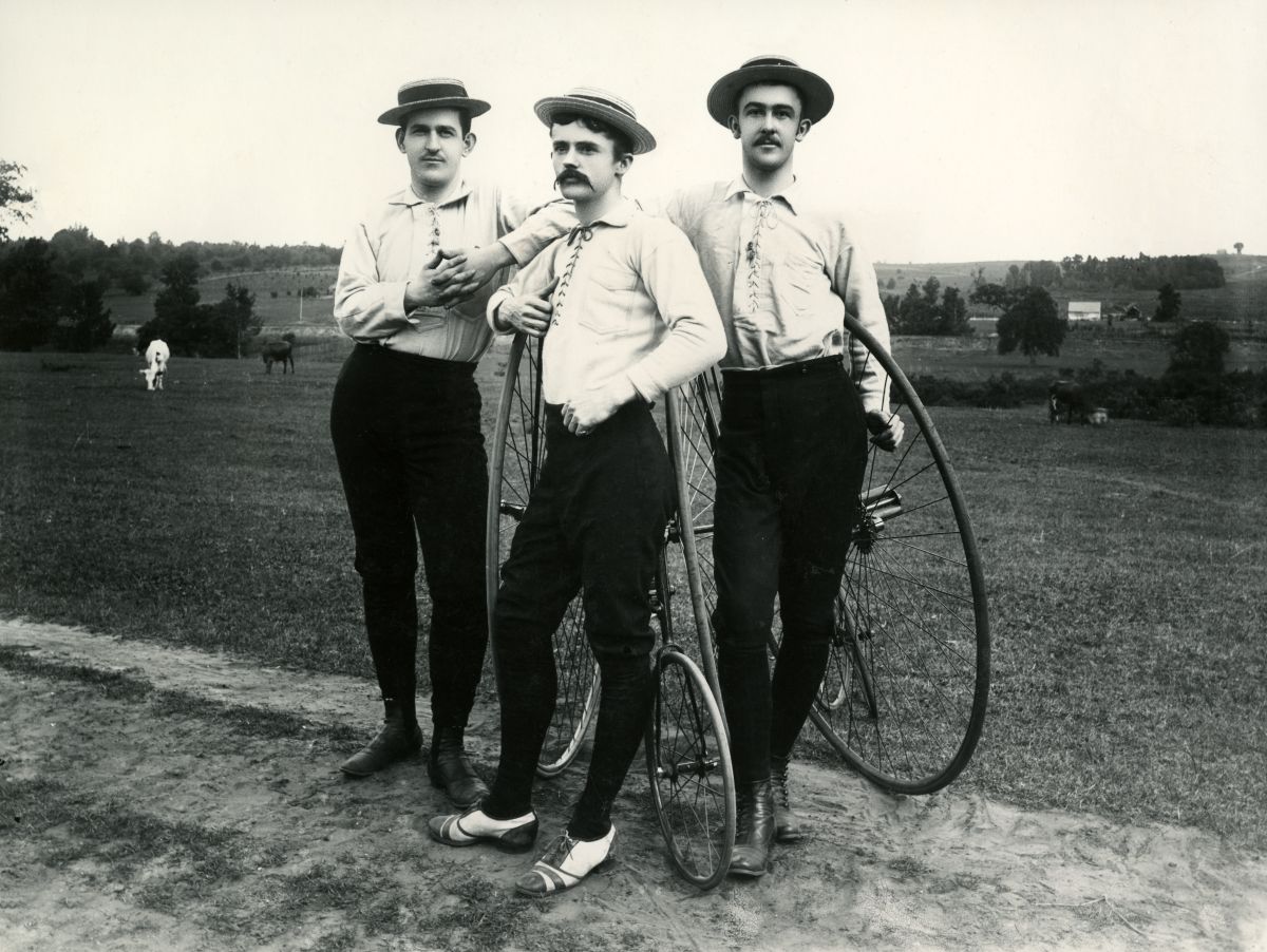 Three young men with Penny-Farthing bicycles