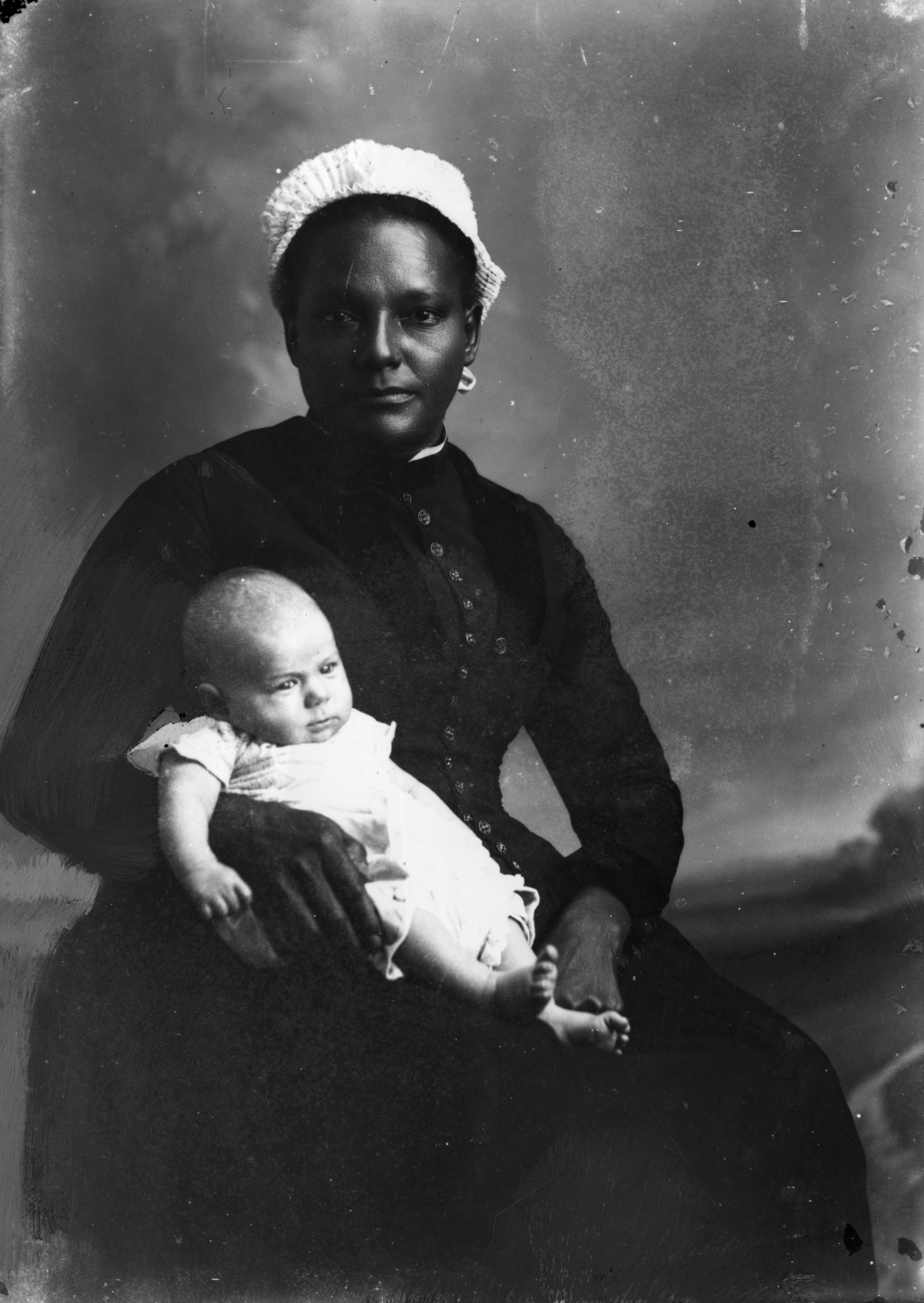 White-capped nurse holding an infant