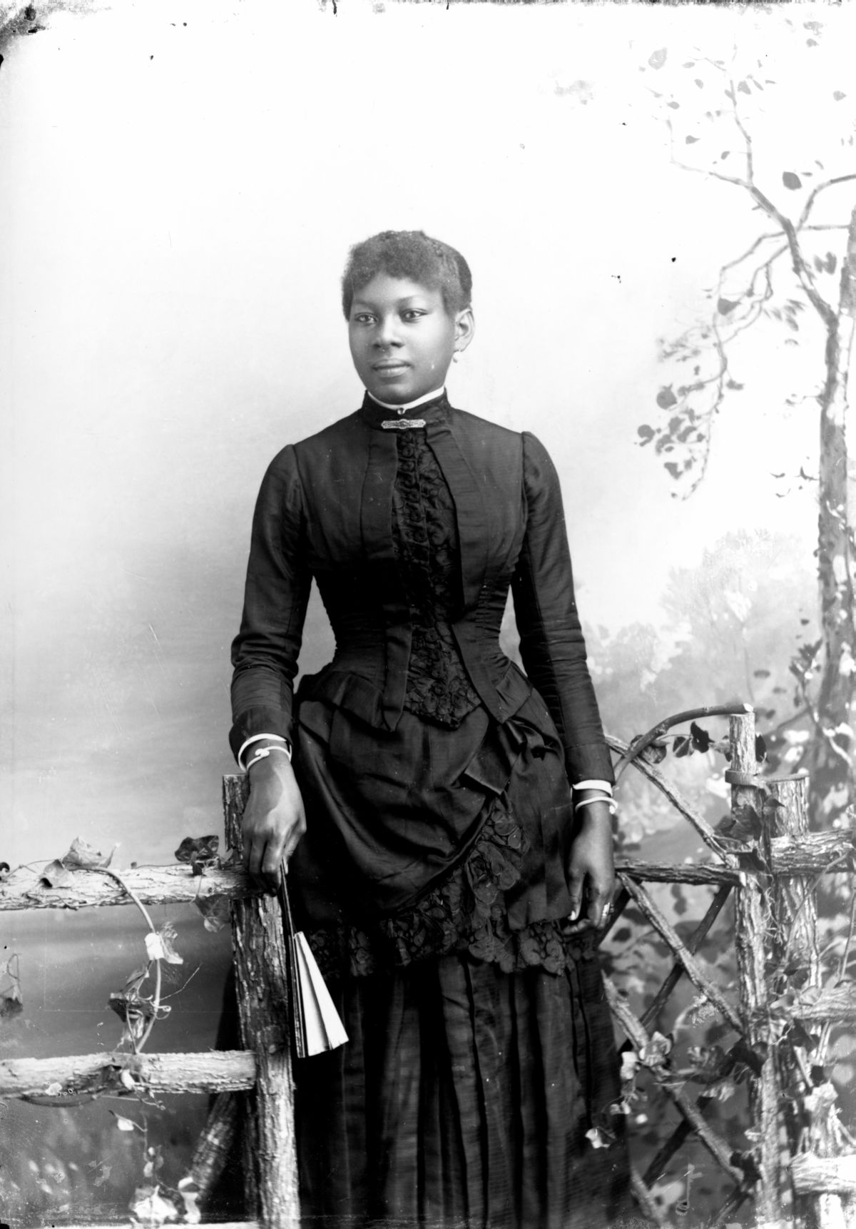 Woman in dark dress, holding a fan