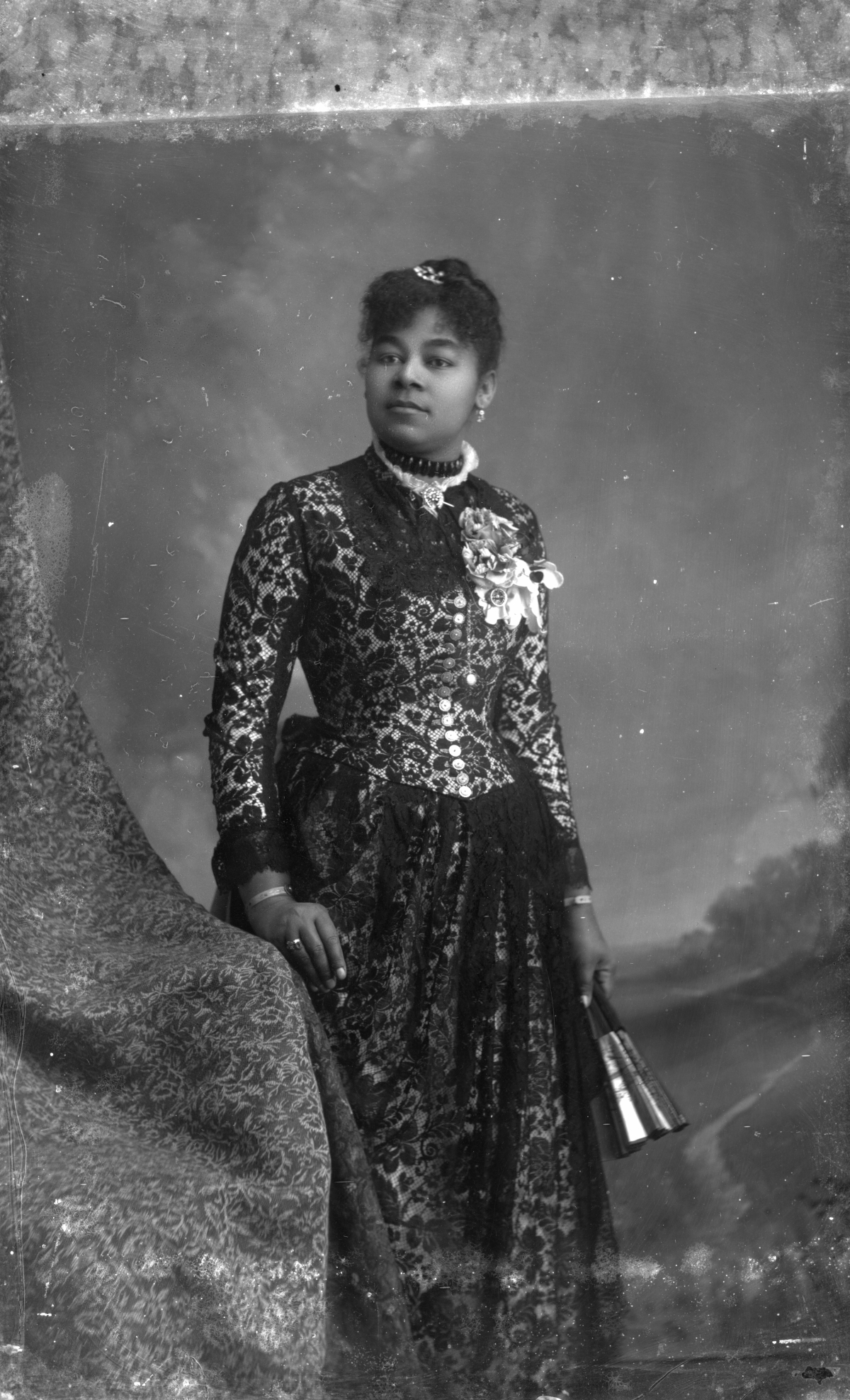 Woman in lace-overlay dress, holding a fan
