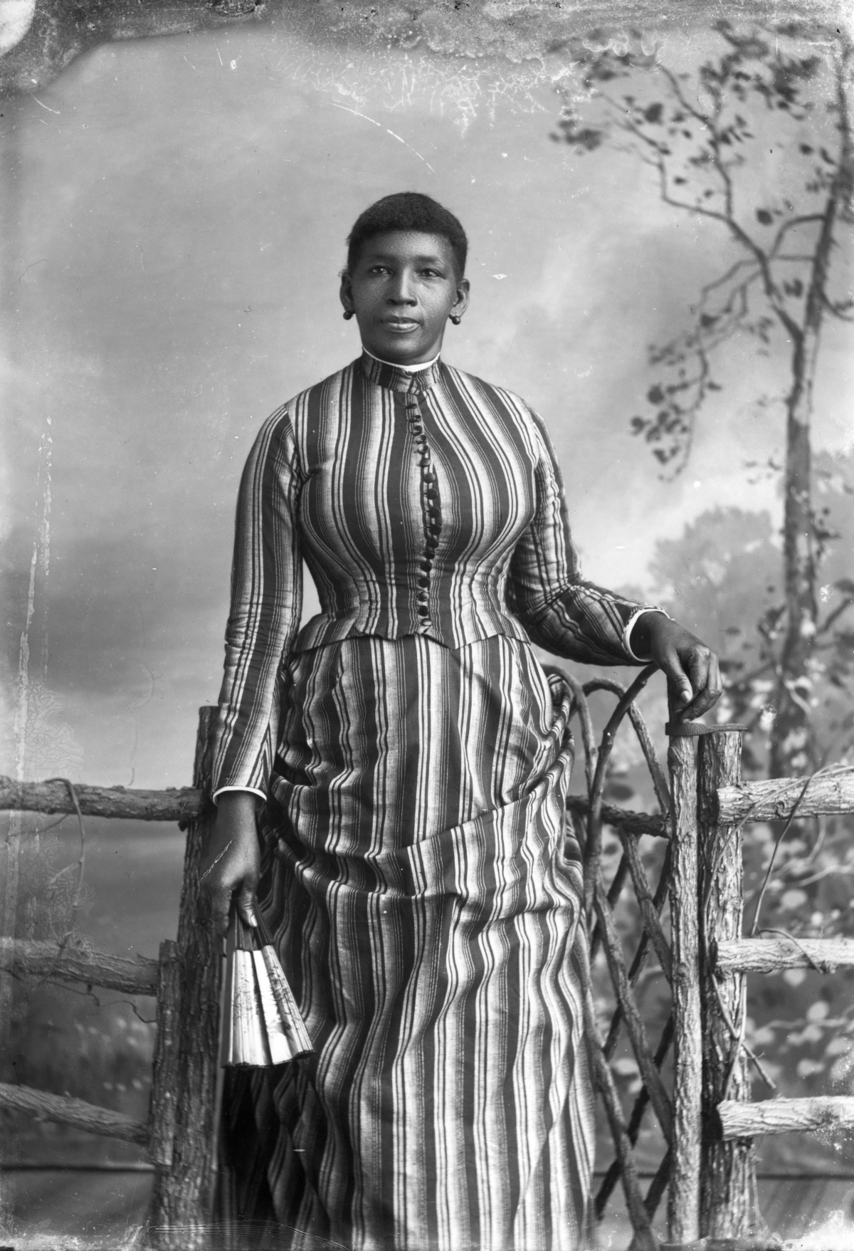 Woman in striped dress, holding a fan