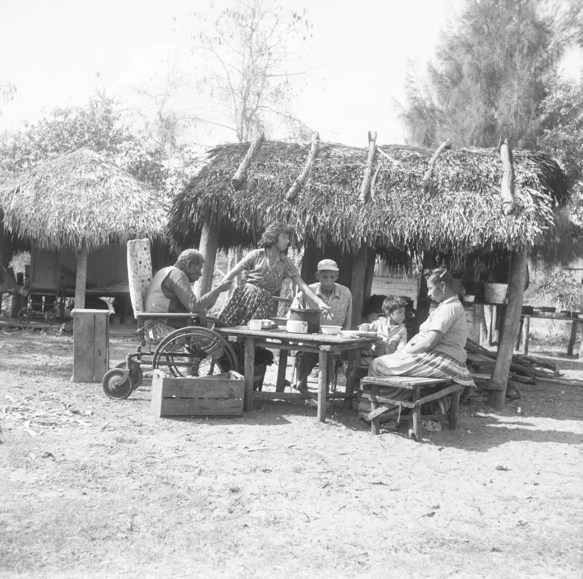 Seminole Indians sitting around a table, in front of chickee - Charlie Dixie Camp, Florida