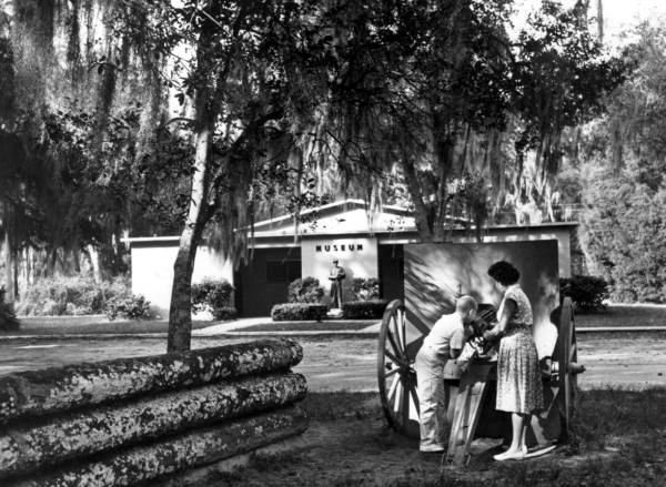 Park visitors with Gatling gun in front of museum at Dade Battlefield Historic Historic Park - Bushnell, Florida