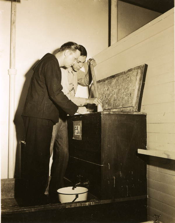 Naval Photography School instructor showing student how to mix photographic chemicals at NAS Pensacola.