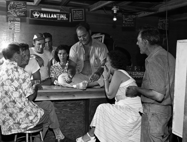 Bartender Chiz Rivers striking a match on his bare foot for a customer in Naples, Florida.