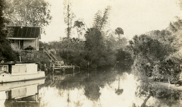 Postcard showing a scenic view of the Estero River in front of the Koreshan Unity medical cottage.