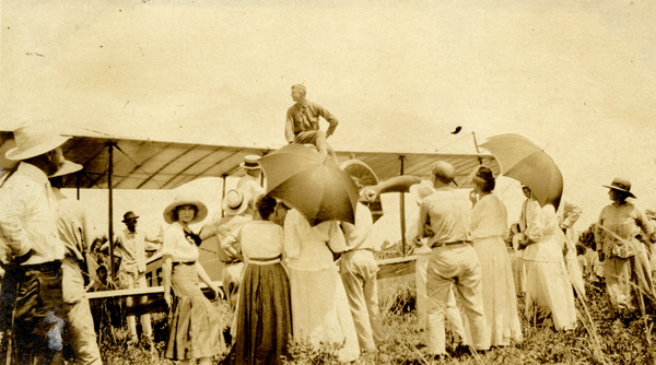 Postcard showing crowd gathered around an airplane.