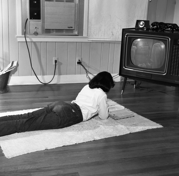 Tallahassee teen reading in front of the t.v.