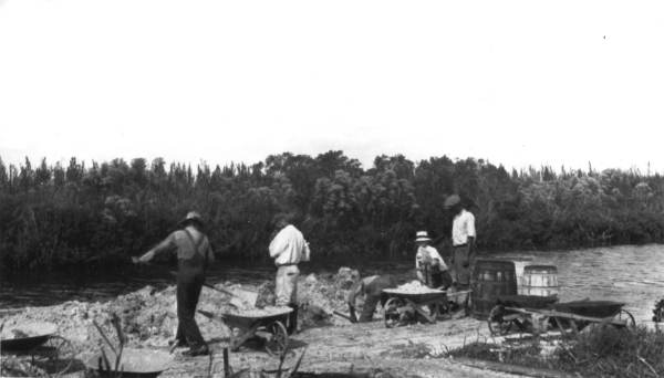 Loading wheelbarrows with sandy clay from the river