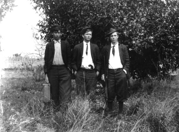 One young man with a suitcase, one with a handgun and one with a shotgun.