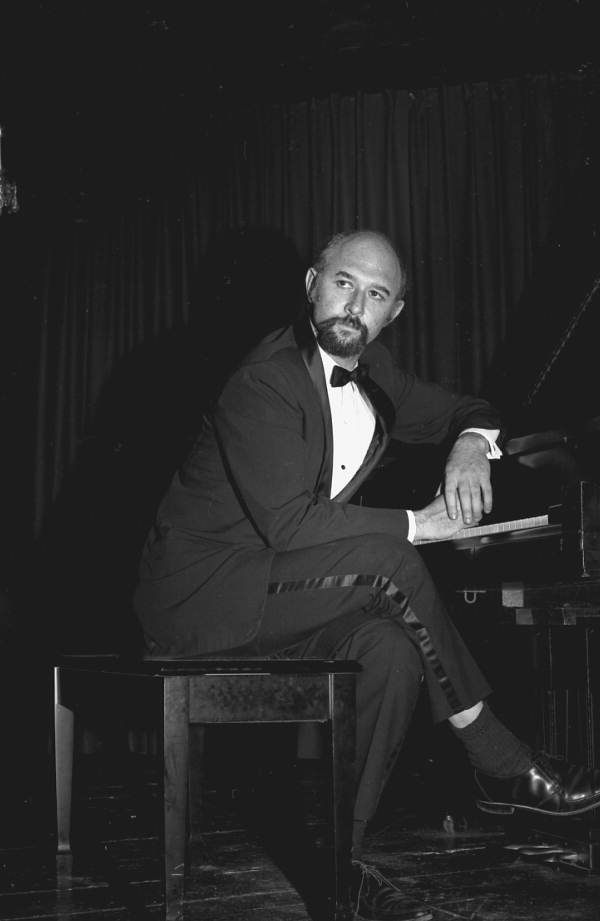Portrait of concert pianist Yehuda Guttman leaning against piano at the Red Barn Theatre - Key West, Florida.