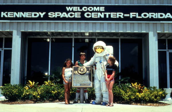 Person wearing space suit standing with visitors in front of the Kennedy Space Center on Merritt Island near Titusville, Florida.
