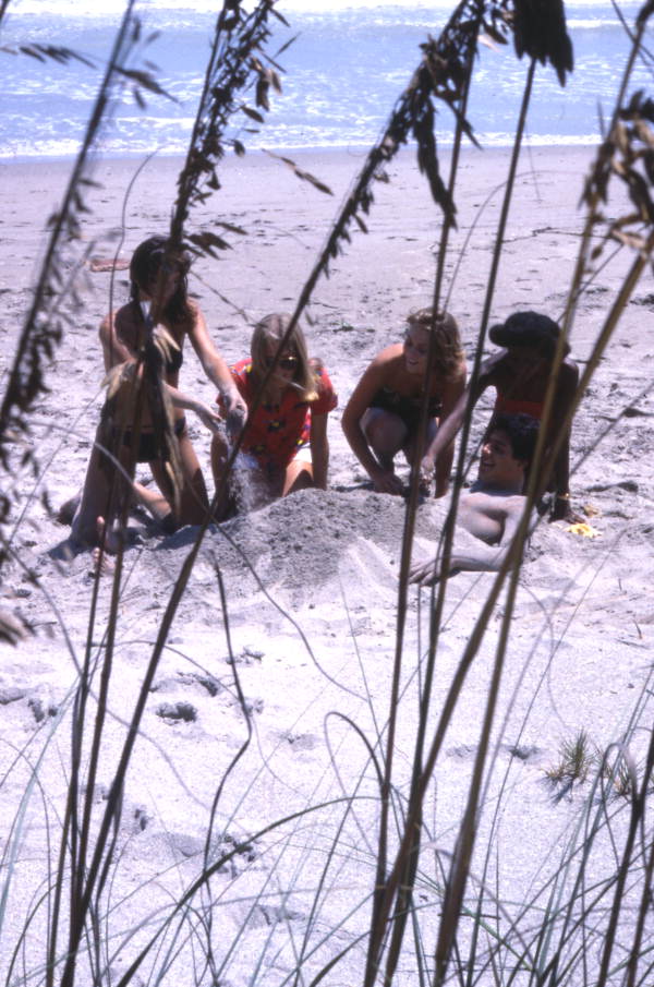 Young women burying a man in the sand at the Hutchinson Island beach.