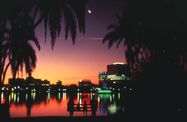 Evening lakeside view of Orlando skyline during sunset.