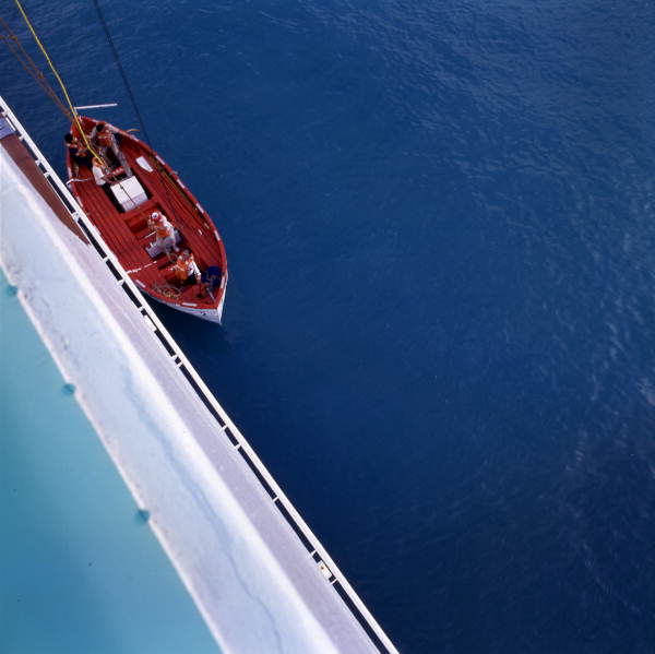 Lifeboat being lowered from the side of a cruise ship.