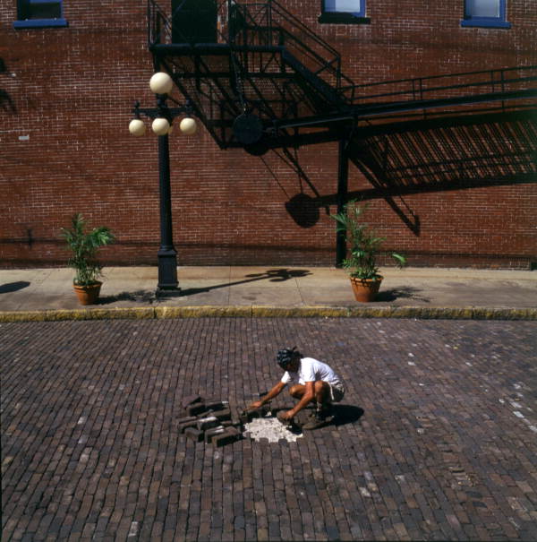 Worker placing bricks in a street in the Ybor City Historic District of Tampa, Florida.