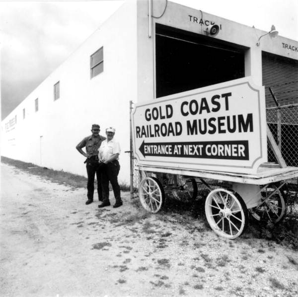 Two employees stand by the sign of the Gold Coast Railroad Museum - Fort Lauderdale, Florida.