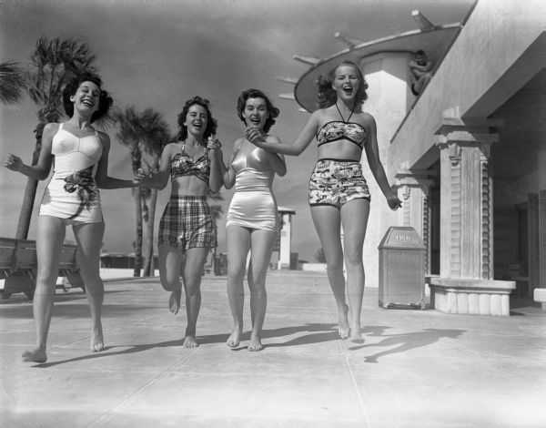 Young women holding hands sauntering in front of a casino - Lido Beach, Florida.