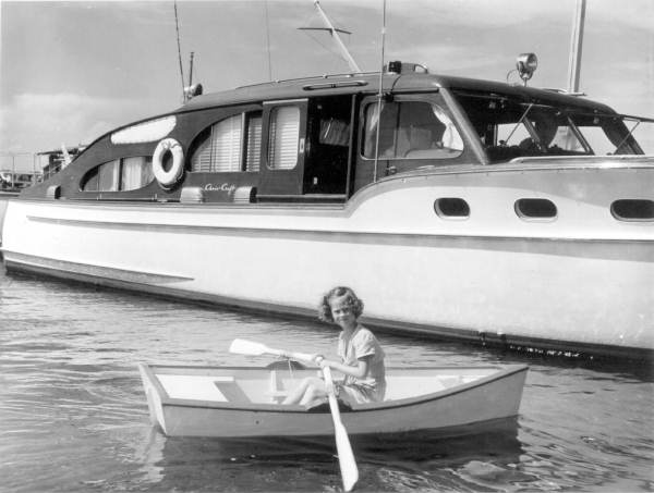 Sally Marbury rows next to a yacht in her miniature dinghy