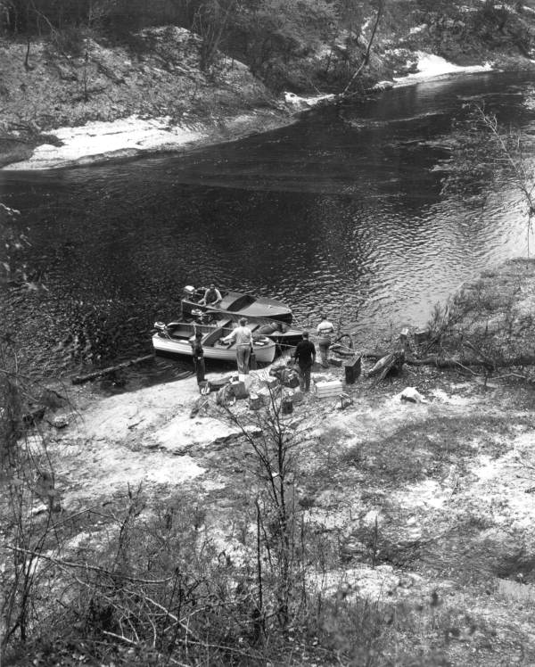 Men board boats on the river .