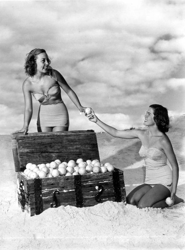 Ann Williamson (left) and Jane Strickland in a beach scene, posing with orange-filled treasure chest - Winter Haven, Florida