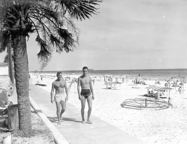 View of a couple of fellows walking along the beach.