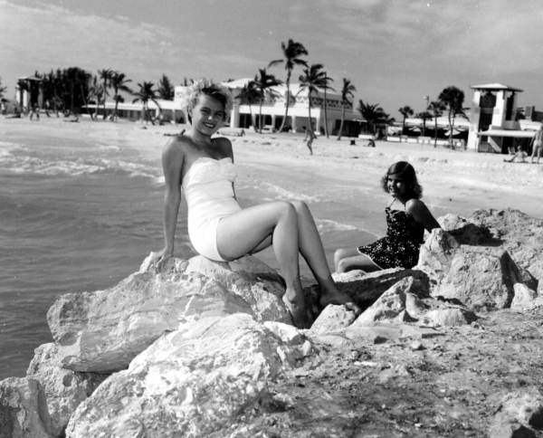 Young women pose on rocks at the beach.