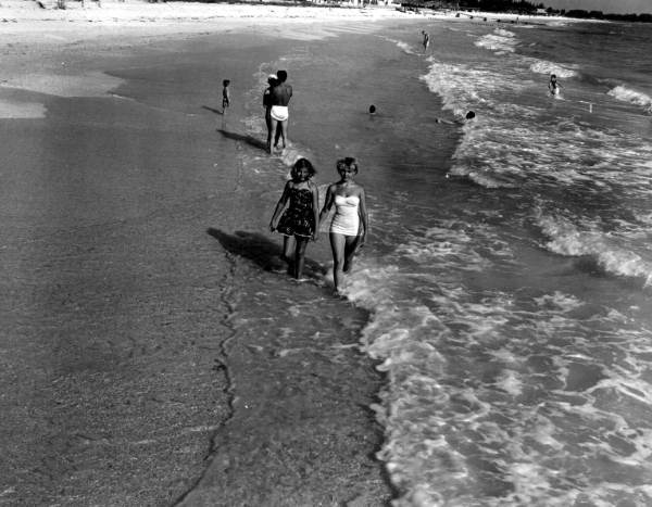 Young women walk together through the water.