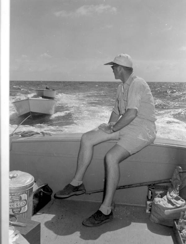 A man sits on the side of a boat watching two hauled dinghies - Dry Tortugas, Florida.