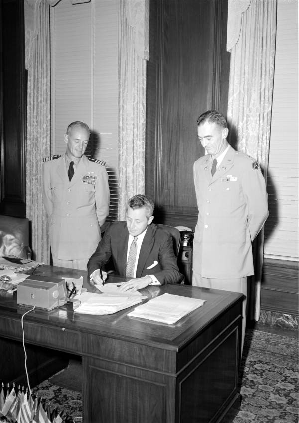 Governor LeRoy Collins signing document for U.S. Navy Captain Winslow and unidentified man.