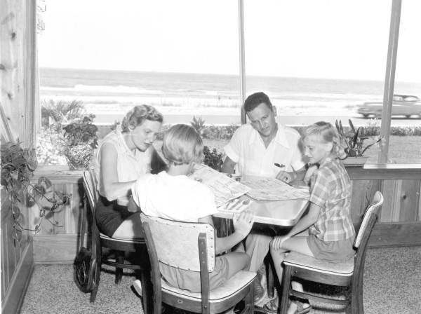 Family reading menus in a restaurant overlooking the beach.