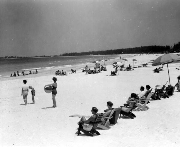 People sunbathing in wooden lounge chairs.