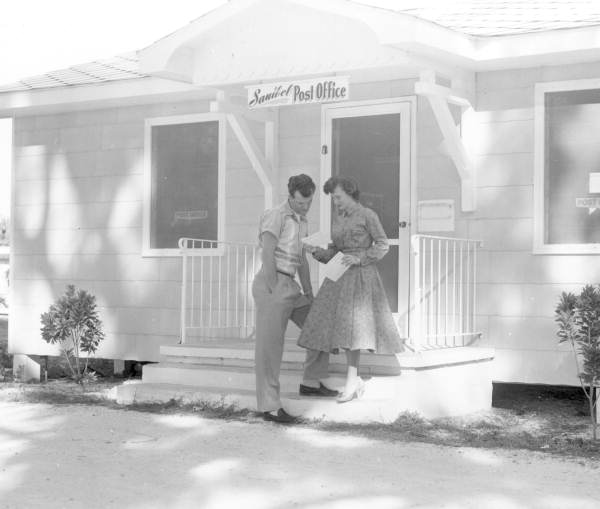 Honeymooners Lyn and Jim Agramonte reading letters in front of a post office - Sanibel Island, Florida.