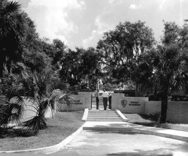 Park ranger and tourist looking at the Ribault Monument in the Fort Caroline National Memorial.