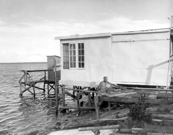 Unidentified man works on a dock behind a building - Card Sound, Florida.