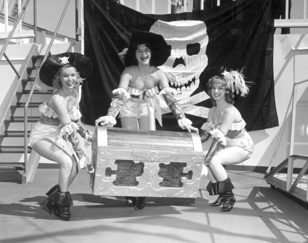 Three young women pose with a treasure chest at the Gasparilla Festival - Tampa, Florida.