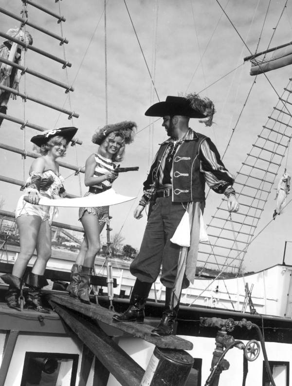 Two young women make a pirate "walk the plank" during the Gasparilla festival - Tampa, Florida.