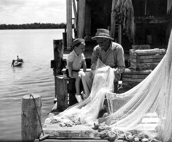 Fisherman mending net as boy watches - Marco Island, Florida