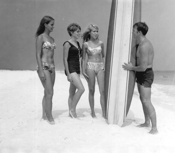 Unidentified man shows his surfboard to three young women - Pensacola, Florida .