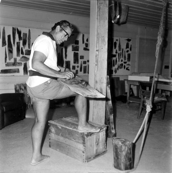 Artist working on driftwood and acrylics to make pelicans.