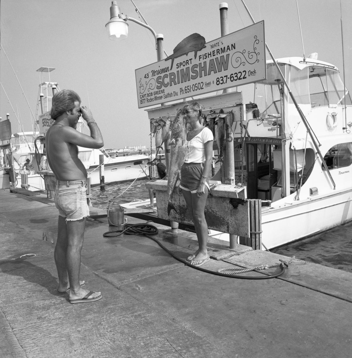 A man taking a picture for a young woman in front of a charter boat - Destin, Florida