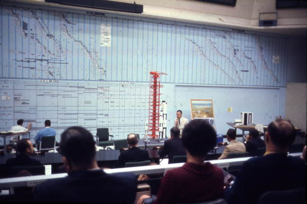Man with rocket models speaking to audience at Cape Canaveral.
