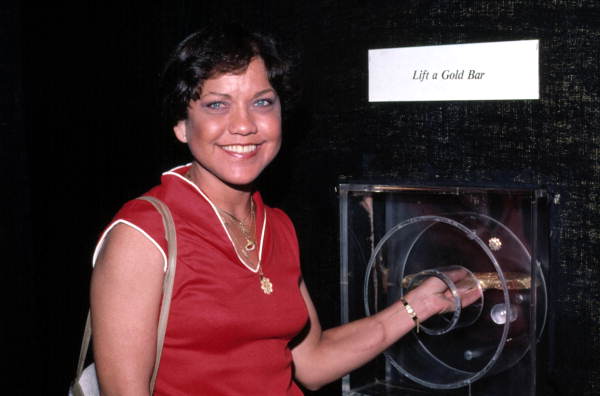 Ann McDonald lifts gold bar from the "Atocha" treasure display at Mallory Square..