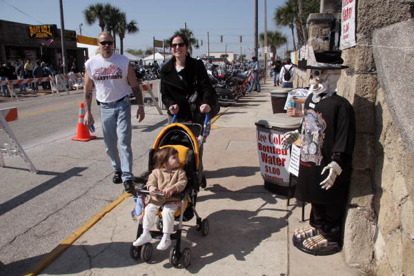 Woman pushing a toddler in stroller on Main Street during Bike Week 2006 - Daytona Beach, Florida.