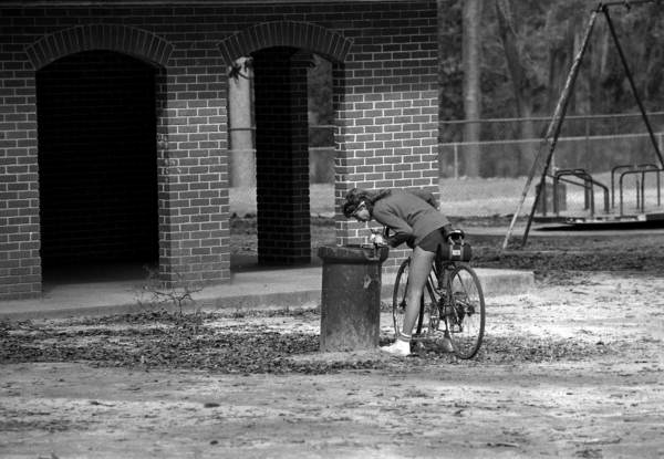 Bicyclist drinks from a drinking fountain in the park - Tallahassee, Florida.