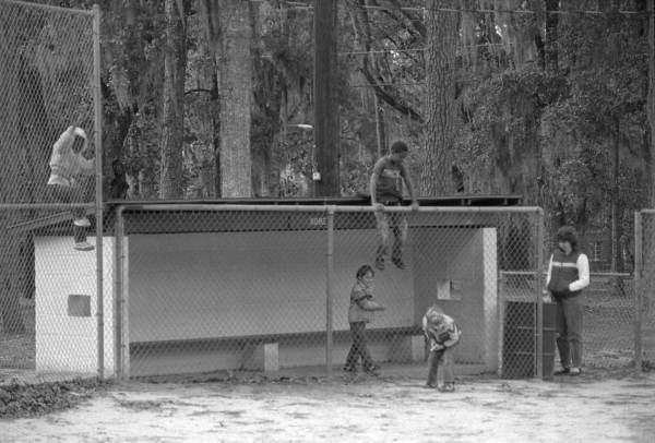 Children play on chain link fence near the dugout - Tallahassee, Florida.